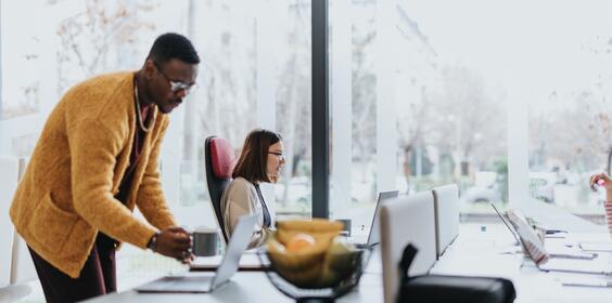 A man and woman sit behind their computers at the office. 